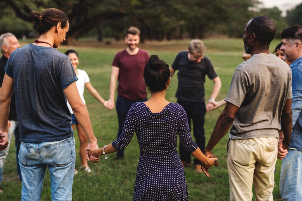 Group of people holding hand together in the park adultes en cercle debout mains jointes